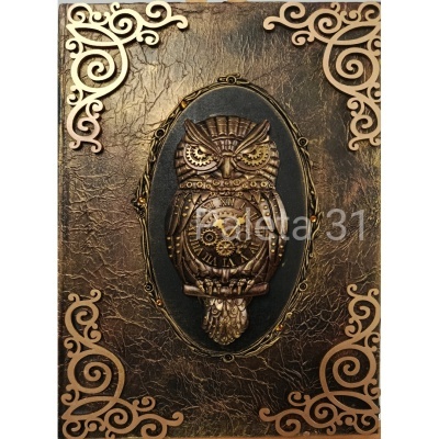 Caderno com capa texturizada castanha, coruja metálica em relevo e cantos decorativos em madeira clara