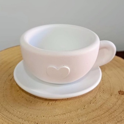 Chávena e pires brancos em cerâmica com relevo de coração, sobre superfície de madeira