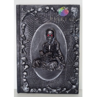 Livro ou diário com capa em relevo de esqueleto e crânios em tons cinza e preto