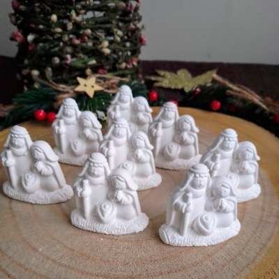 Conjunto de figuras brancas de presépio em cerâmica sobre base de madeira redonda