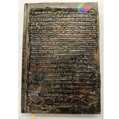 Caderno em capa dura castanho envelhecido com texto em relevo e moldura decorativa dourada.