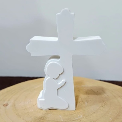 Figura decorativa branca de criança ajoelhada a rezar junto a cruz sobre base de madeira