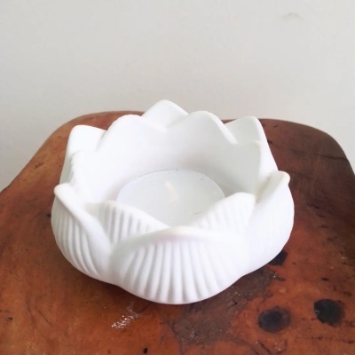 Suporte de vela branco em forma de flor sobre madeira