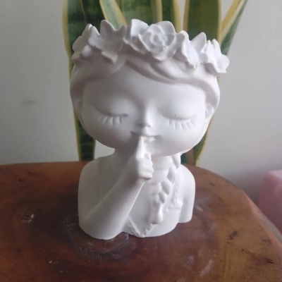 Figura decorativa branca de criança com coroa de flores