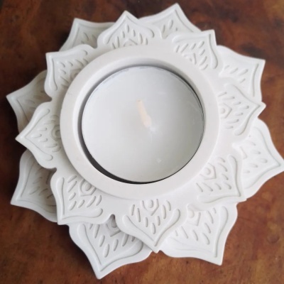 Vela branca em castiçal decorativo branco com padrão de pétalas em relevo