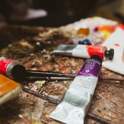 tubos de tinta óleo, pincéis e paleta de pintura sobre superfície manchada