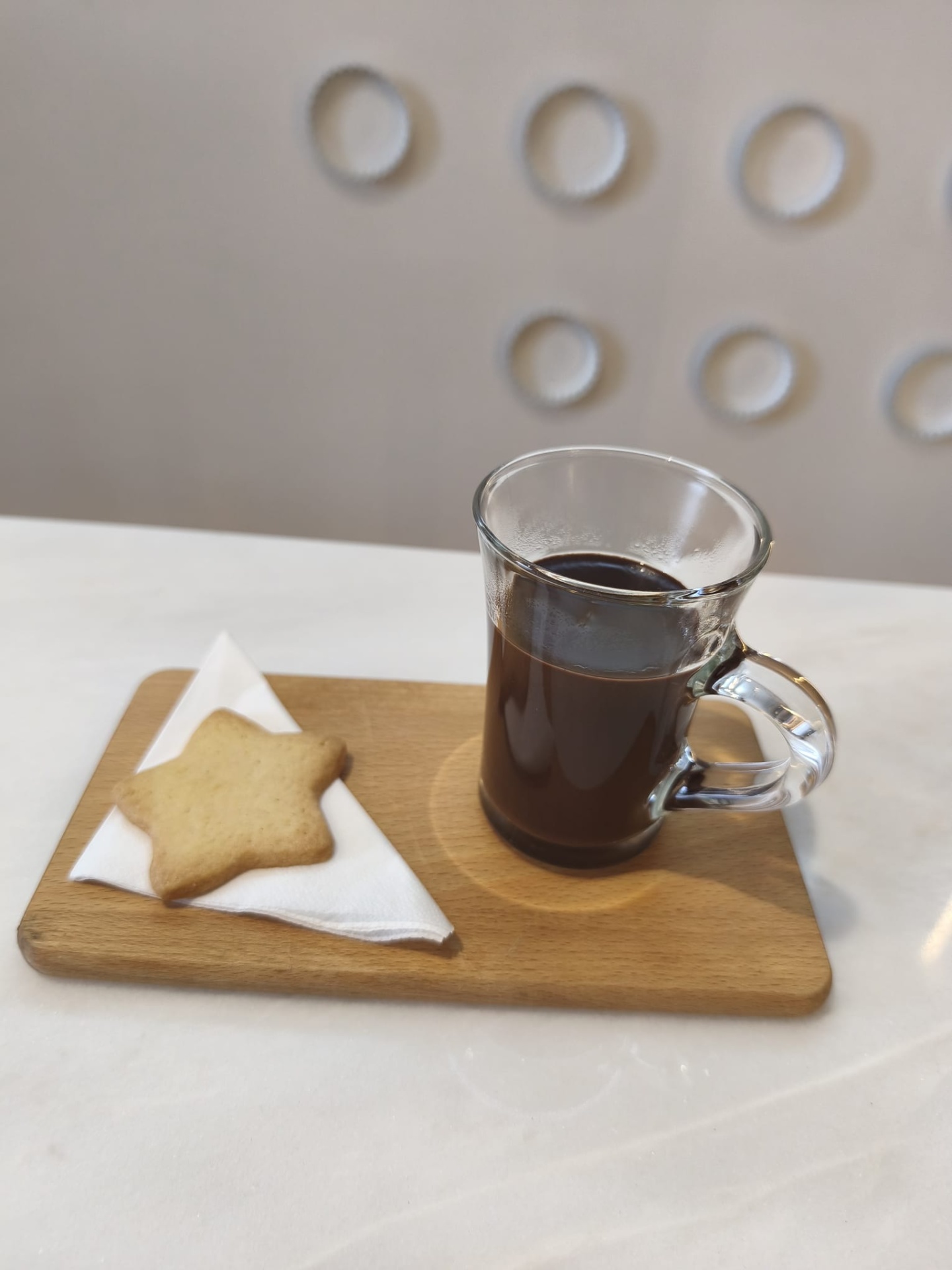 Chávena de vidro com café e biscoito em forma de estrela numa tábua de madeira