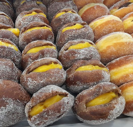 Sonhos com recheio amarelo polvilhados com açúcar em filas