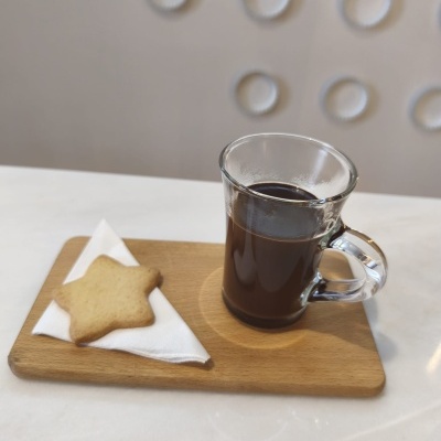 Chávena de vidro com café e biscoito em forma de estrela numa tábua de madeira
