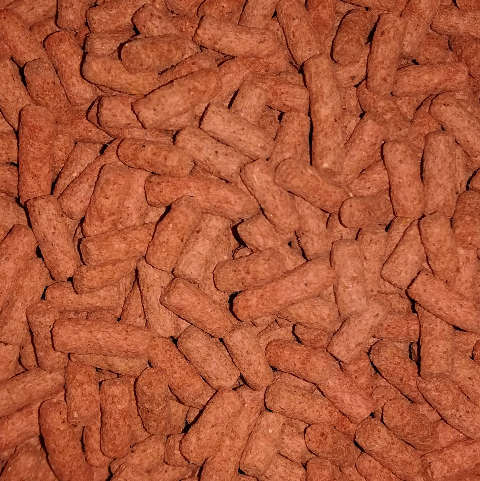 Sticks Cichlid Pellets cilíndricos castanhos compactos com textura rugosa em disposição densa