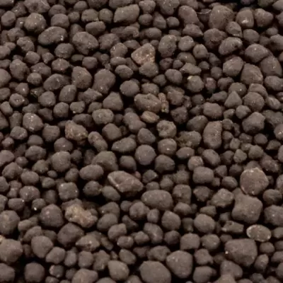 Pellets pequenos castanho escuro com textura rugosa.