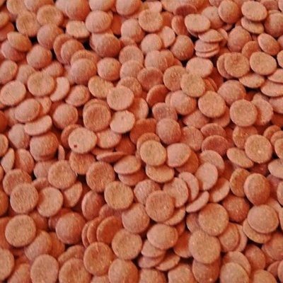 Muitas pastilhas redondas castanhas alaranjadas num fundo indeterminado