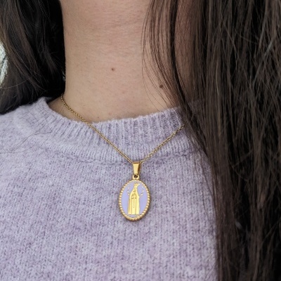 Colar dourado com pendente oval lilás com figura religiosa, usado com camisola lilás