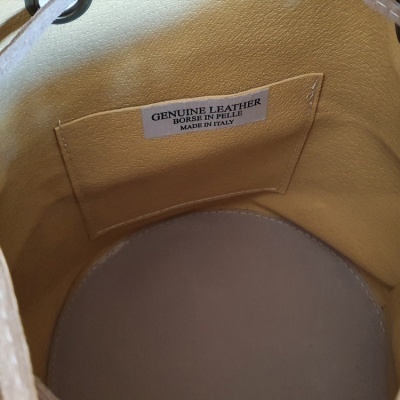 Interior de bolsa em couro amarelo com etiqueta de couro genuíno