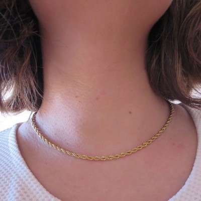Colar dourado fino entrelaçado no pescoço