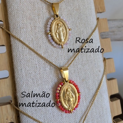 Dois colares com pendentes de medalha dourada de Nossa Senhora, um com contas rosa matizado e outro com contas salmão matizado em suporte bege