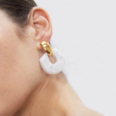 Brinco dourado com pendente branco marmoreado numa orelha