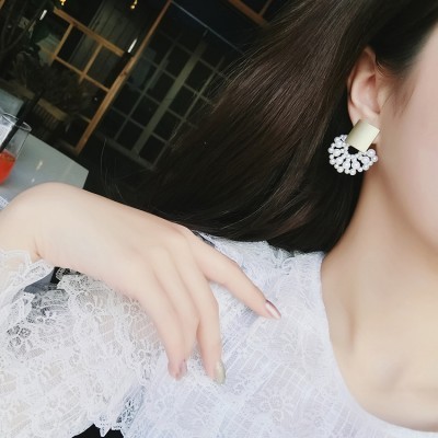 Brinco com base dourada opaca e pérolas brancas em forma de meia lua.