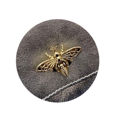 Costura branca em pele cinzento e abelha dourada em metal