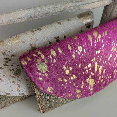 Três carteiras de diferentes cores e texturas empilhadas numa superfície branca