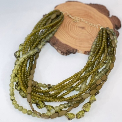 Colar verde multi-fios com várias contas em apresentação sobre base de madeira