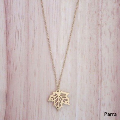 Colar dourado com pendente de folha vazada sobre madeira clara