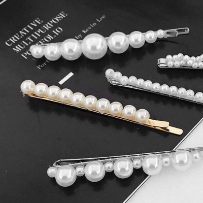 Molas de cabelo decoradas com pérolas sobre livro preto