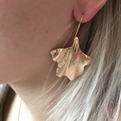 Brinco dourado em forma de folha na orelha