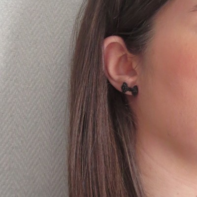 Brinco preto em forma de arco numa orelha com cabelo castanho escuro