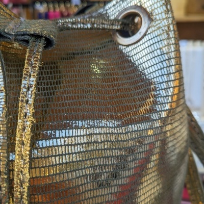 Bolsa dourada com padrão quadriculado e cordão de fechamento