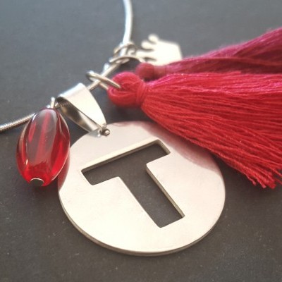 Colar com pendente redondo metálico com letra T, pompom vermelho e pedra vermelha