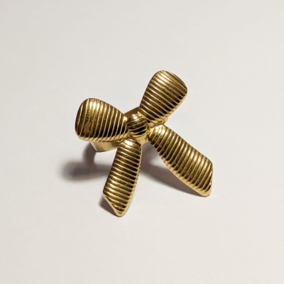 Anel dourado em forma de laço com relevo em linhas paralelas, sobre fundo branco