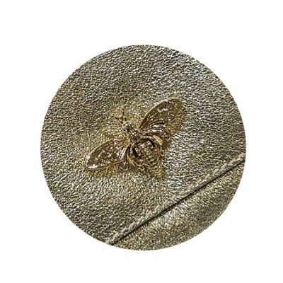 Detalhe de material dourado texturado com abelha metálica decorativa