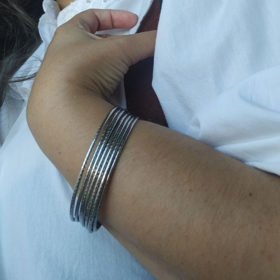 Pulseira de metal prateado com várias voltas no braço