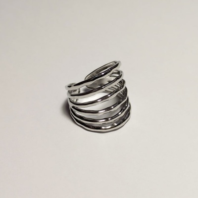 Anel prateado em camadas onduladas numa superfície branca
