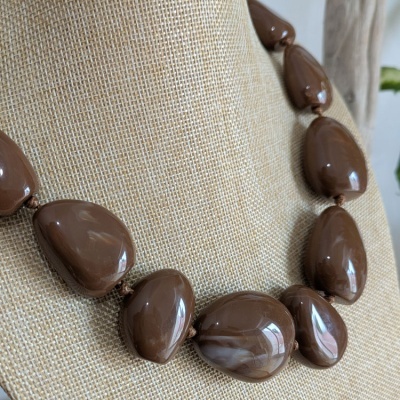 Colar com contas castanhas brilhantes em suporte bege texturado