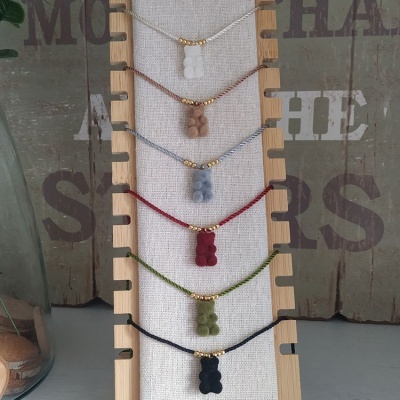 Pulseiras com ursinhos de silicone coloridos em suporte de tecido branco e fundo de madeira