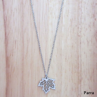 Colar prateado com pendente em forma de folha sobre madeira clara