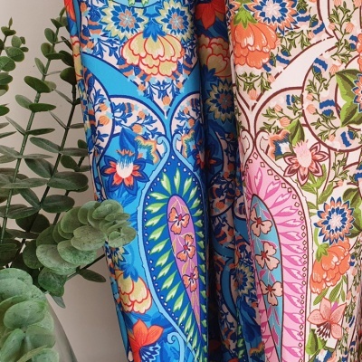 tecido estampado colorido com padrão floral e folhas verdes ao lado