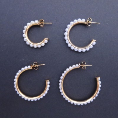 Quatro pares de brincos argola dourados com pérolas em fundo preto