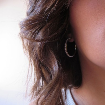 Brinco argola dourado com textura em orelha de mulher