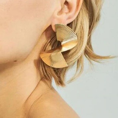Brinco dourado grande com textura em linhas usado na orelha