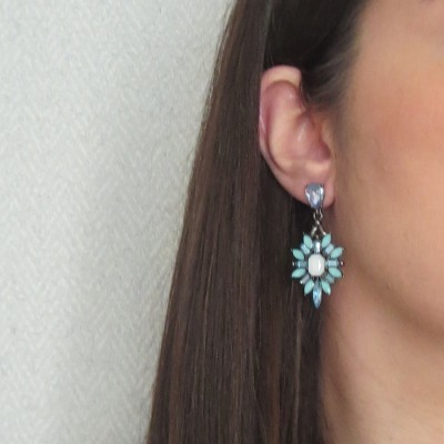 Brinco pendente com pedras azul claro e branca em orelha feminina