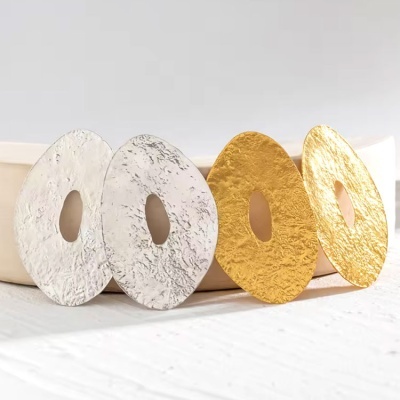 Quatro brincos elípticos, dois prateados e dois dourados, com textura rugosa