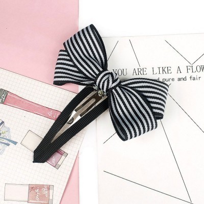 Elástico preto com laço às riscas brancas sobre papéis e fundo rosa