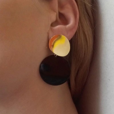 Brinco pendente com discos coloridos e preto usado na orelha direita