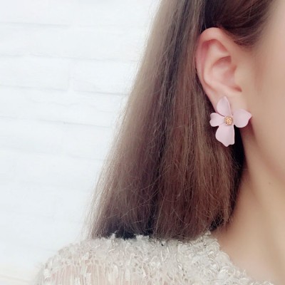 Brinco flor rosa com centro dourado numa orelha de mulher