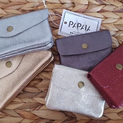 Cinco carteiras pequenas metalizadas com botão de pressão sobre superfície de palha entrelaçada