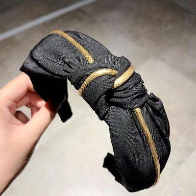 Bandolete preta com linhas douradas e nó central