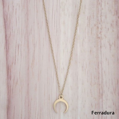 Colar dourado com pendente de lua crescente sobre fundo de madeira